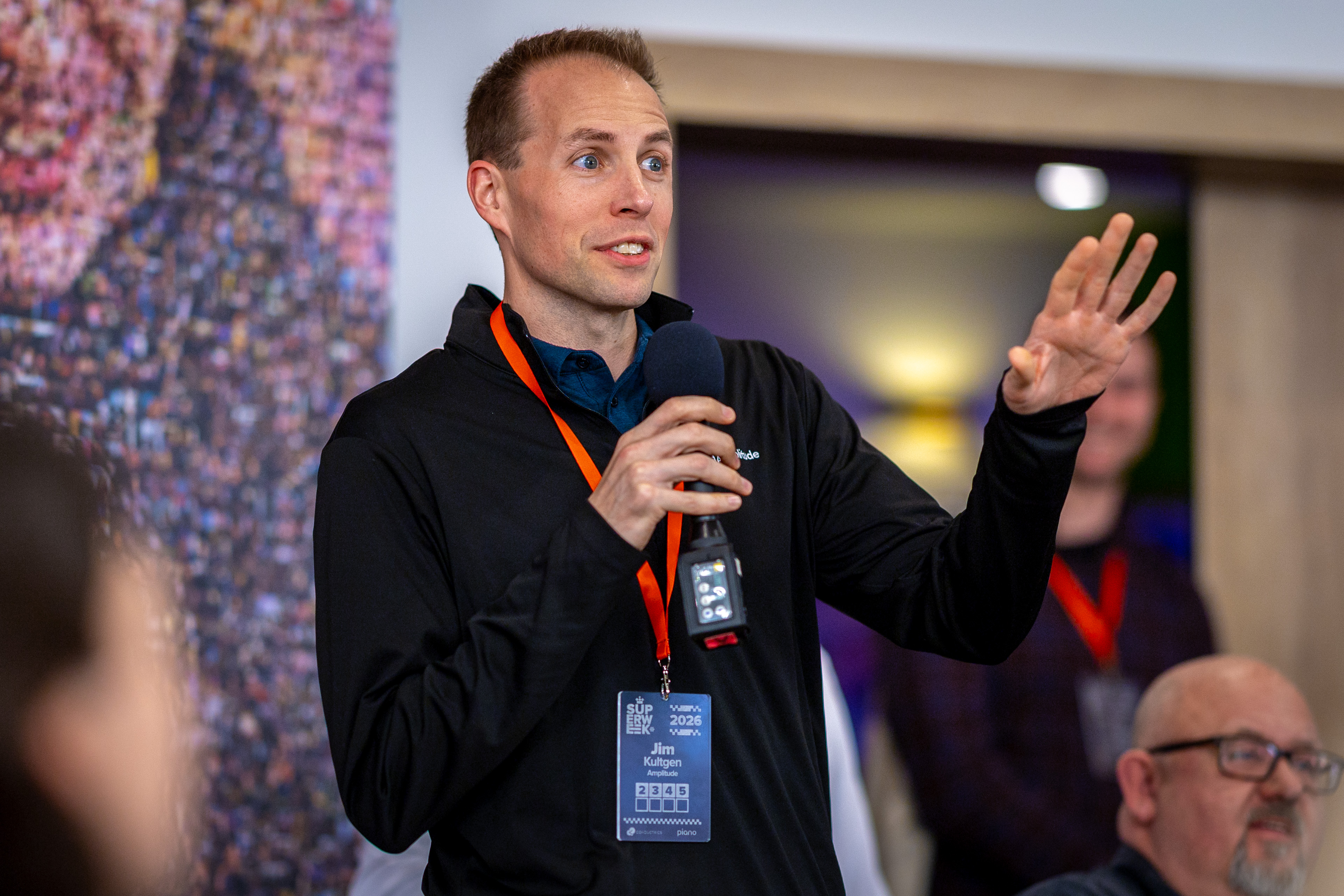 Jim speaking into a microphone and gesturing during a conference discussion